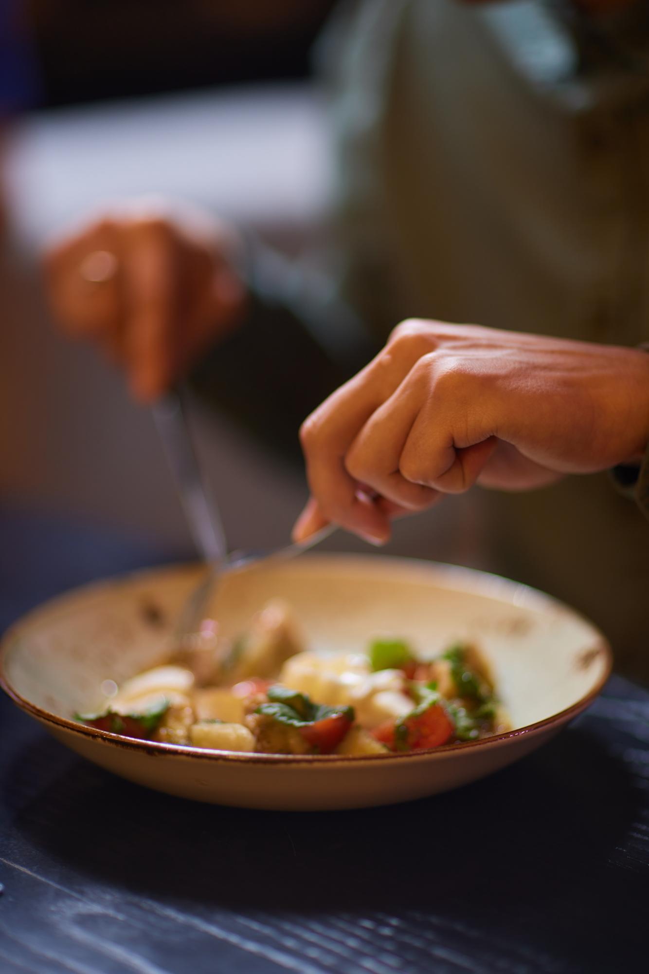 chef hands plating a composed dish on a wooden table